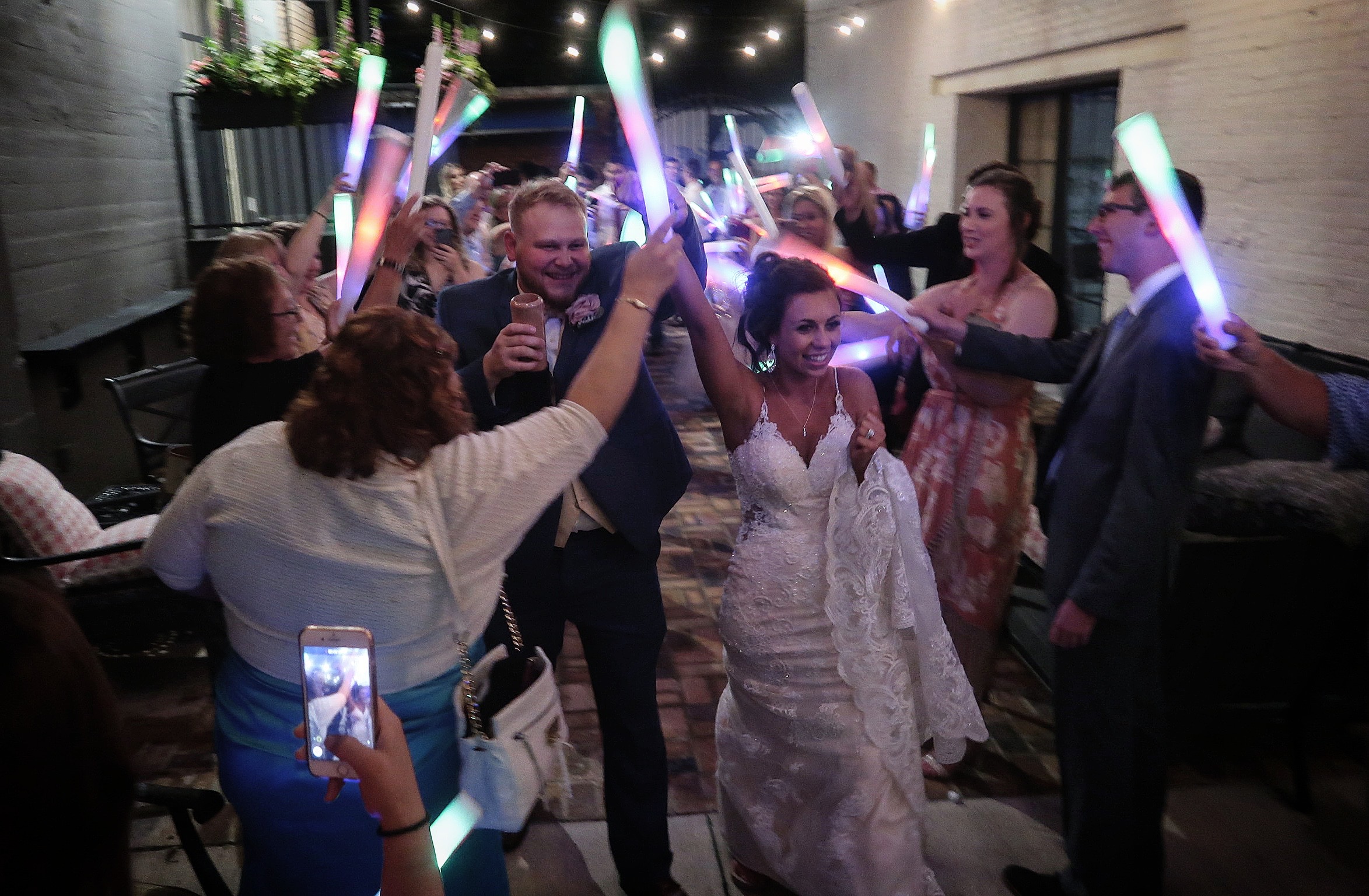 A bride and groom entering a packed Steam Plant dance floor beneath glowing light sticks